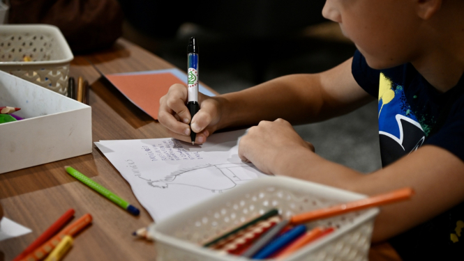 Bērns pie galda ar rakstāmpiederumiem