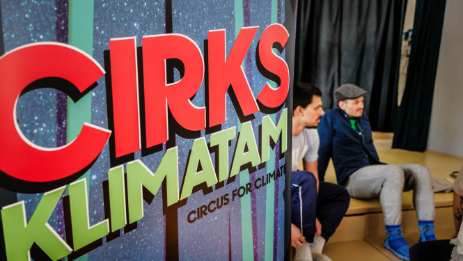 Uzraksts: Cirks klimatam. Divi sēdoši skatītāji.