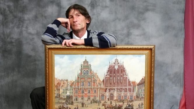 Mākslinieks Sergejs Zinovjevs ar gleznu no izstādes “Mana Rīga”