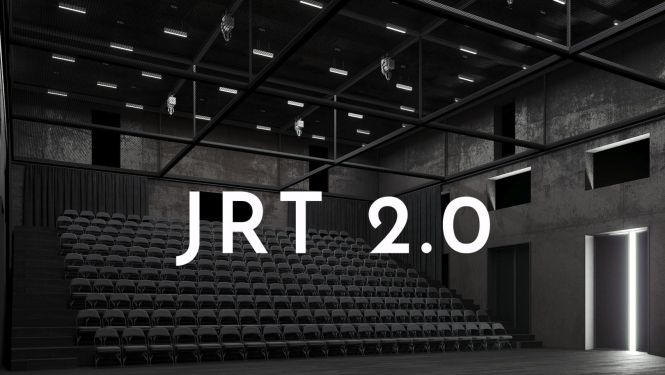 Balts uzraksts "JRT 2.0", fonā skatītāju vietas Jaunā Rīgas teātra pagaidu telpās Tabakas fabrikā