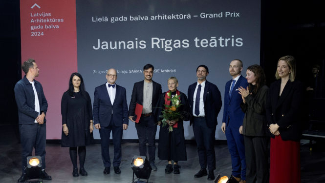 Deviņi cilvēki uz skatuves balvas pasniegšanas laikā