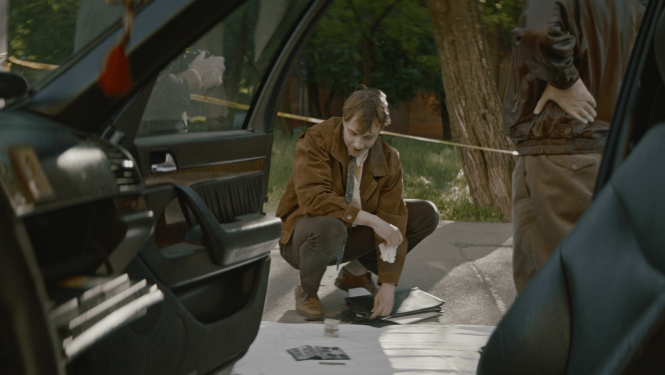 Vīrietis pie mašīnas. Kadrs no filmas.