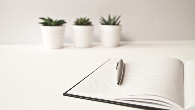 Piezīmju blociņš un pildspalva uz galda