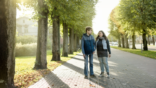 neredzīgs cilvēks ar pavadoni pilsētvidē