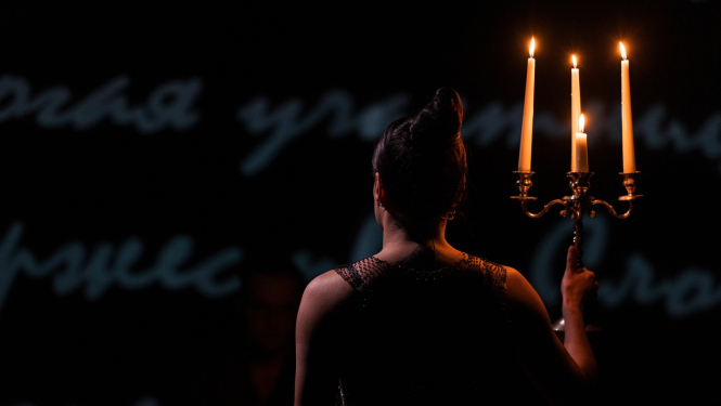 Sieviete ar iedegtām svecēm uz skatuves