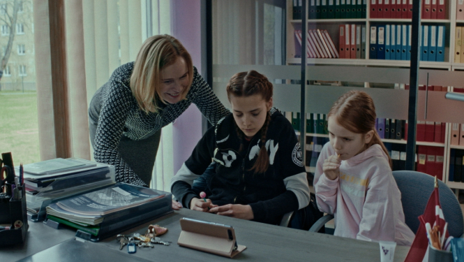 Sieviete un divas meitenes pie galda