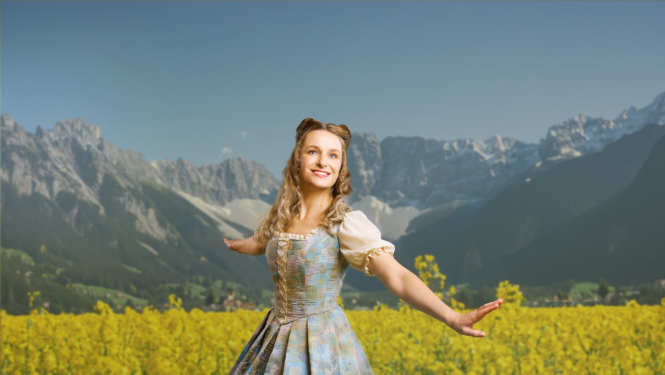 Aktrise uz kalnu fona ziedošā pļavā