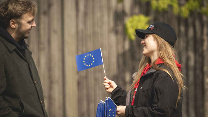 Divi cilvēki, vienam rokās Eiropas Savienības karodziņš