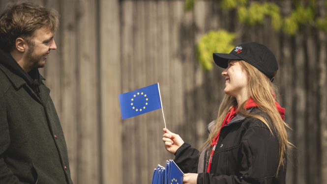 Sieviete tur papīra Eiropas Savienības karodziņus, piedāvā vienu vīrietim