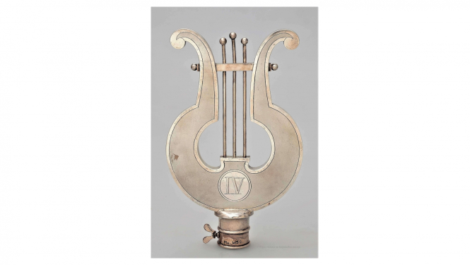 IV vispārējo latviešu dziesmu un mūzikas svētku (Jelgavā) dziesmu kara pirmā godalga – karoga kāta uzgalis, 1895. gads. Saņēmis Rīgas latviešu dziedāšanas biedrības jauktais koris. Izgatavojis meistars Ēriks Bakstats. RVKM krājums.