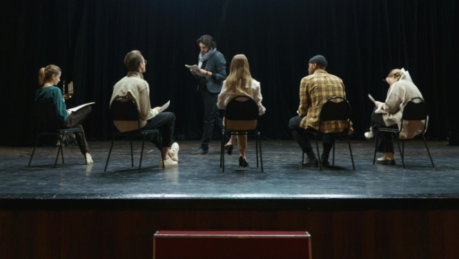 Seši aktieri uz skatuves mēģinājuma procesā