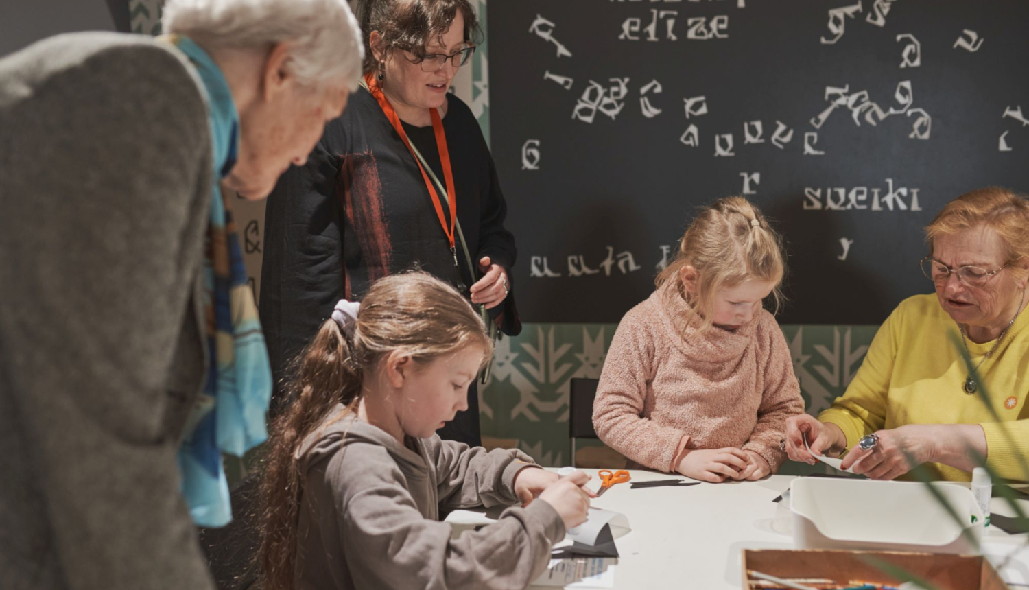 foto redzama Ģimenes dienas norise muzejā, kadrā bērni un pieaugušie radošajā darbnīcā