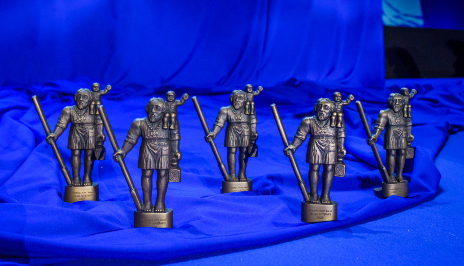 Lielā Kristapa statuetes uz zilas drapērijas fona