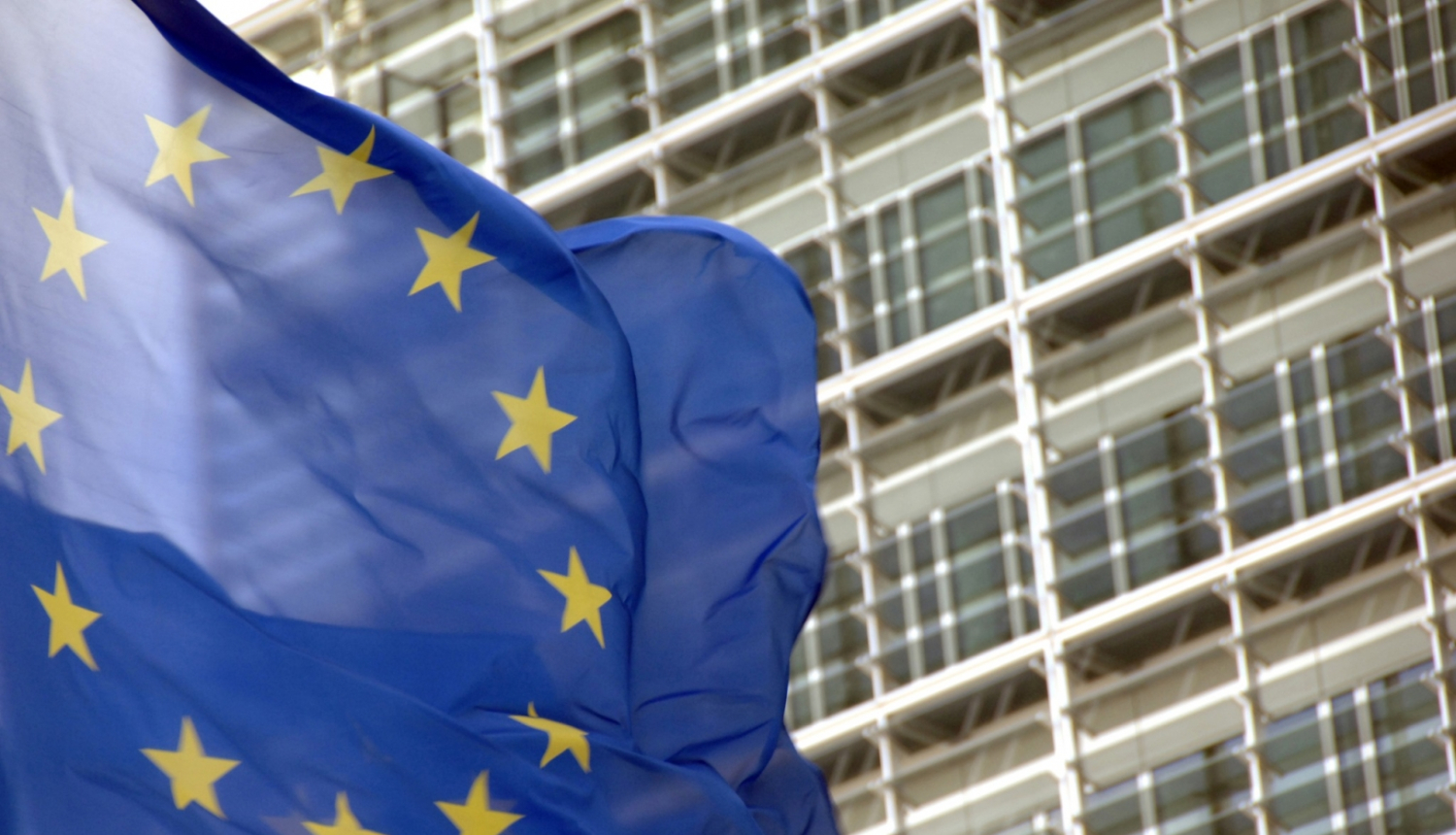 Eiropas Savienības karogs plīvo uz daudzstāvu ēkas fona