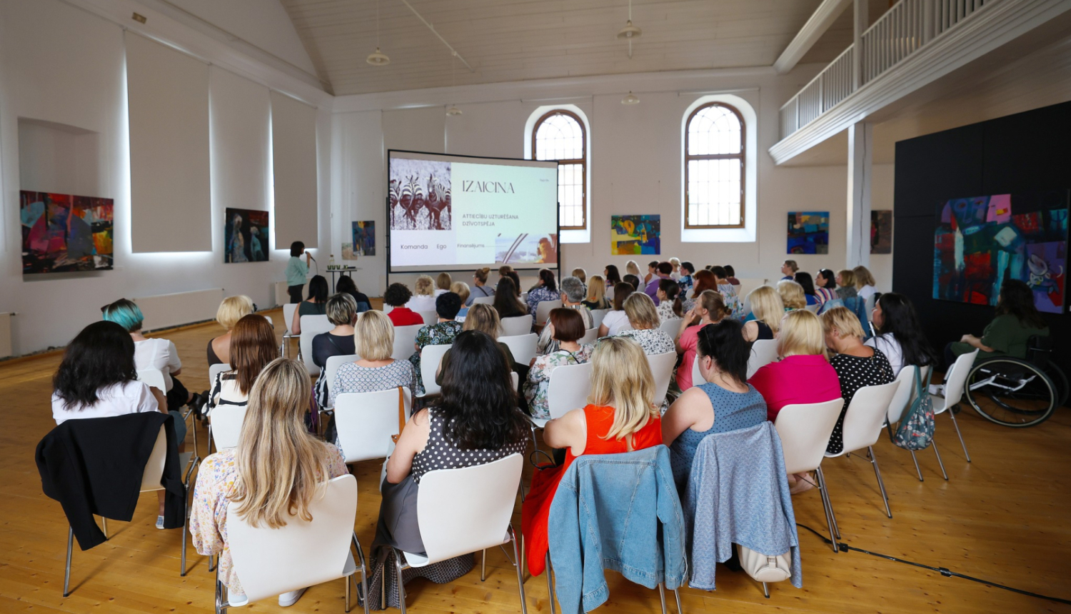 Semināra dalībnieki sēž un klausās prezentāciju 