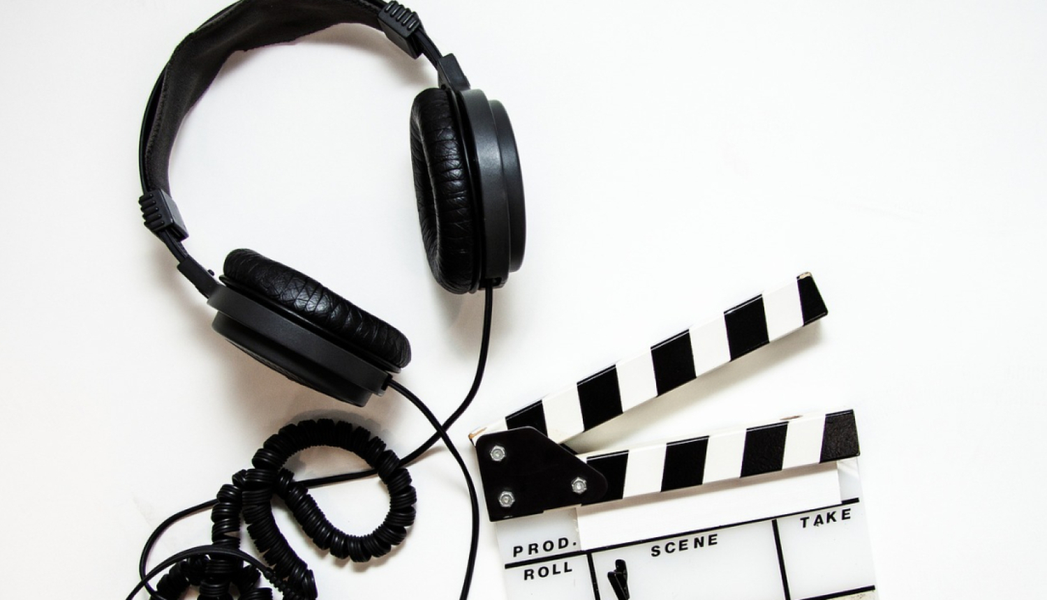 Austiņas ar vadu un filmu klape uz balta fona