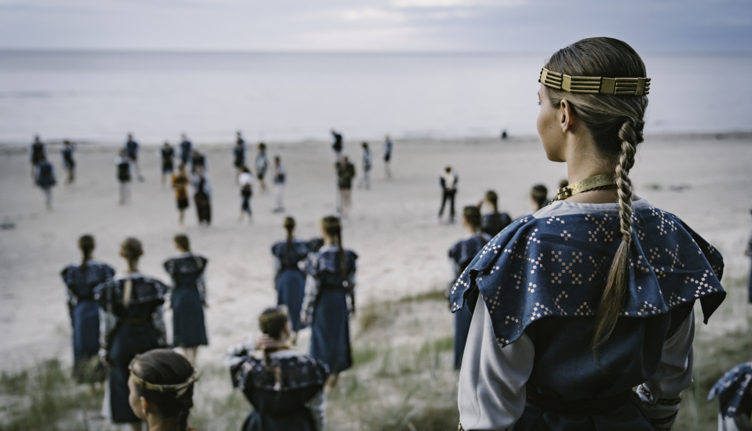 Cilvēki tautastērpos jūras krastā