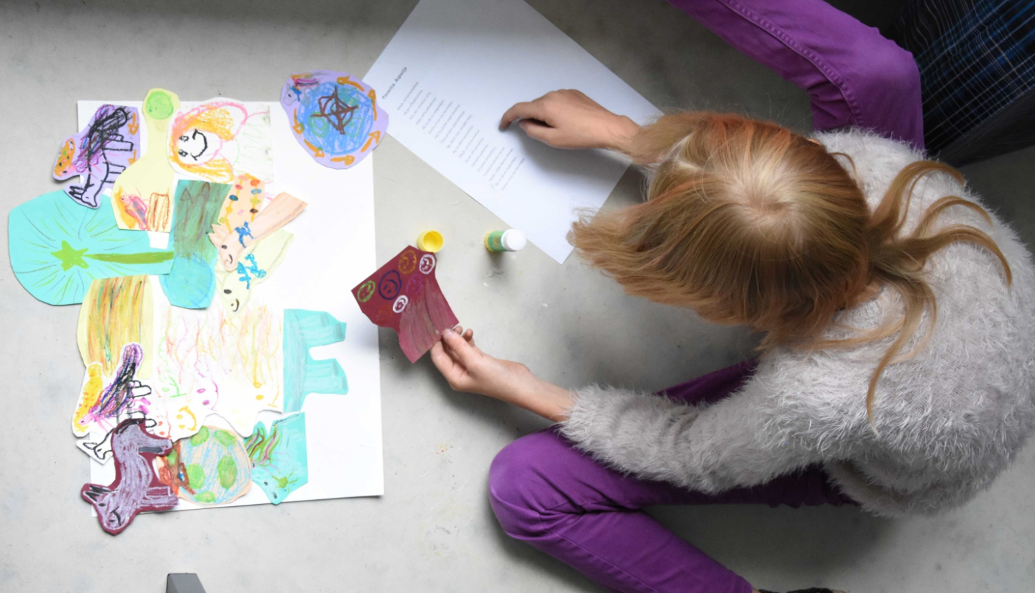 Bērns radošajā darbnīcā ar rakstampiederumiem un papīra izgriezumiem