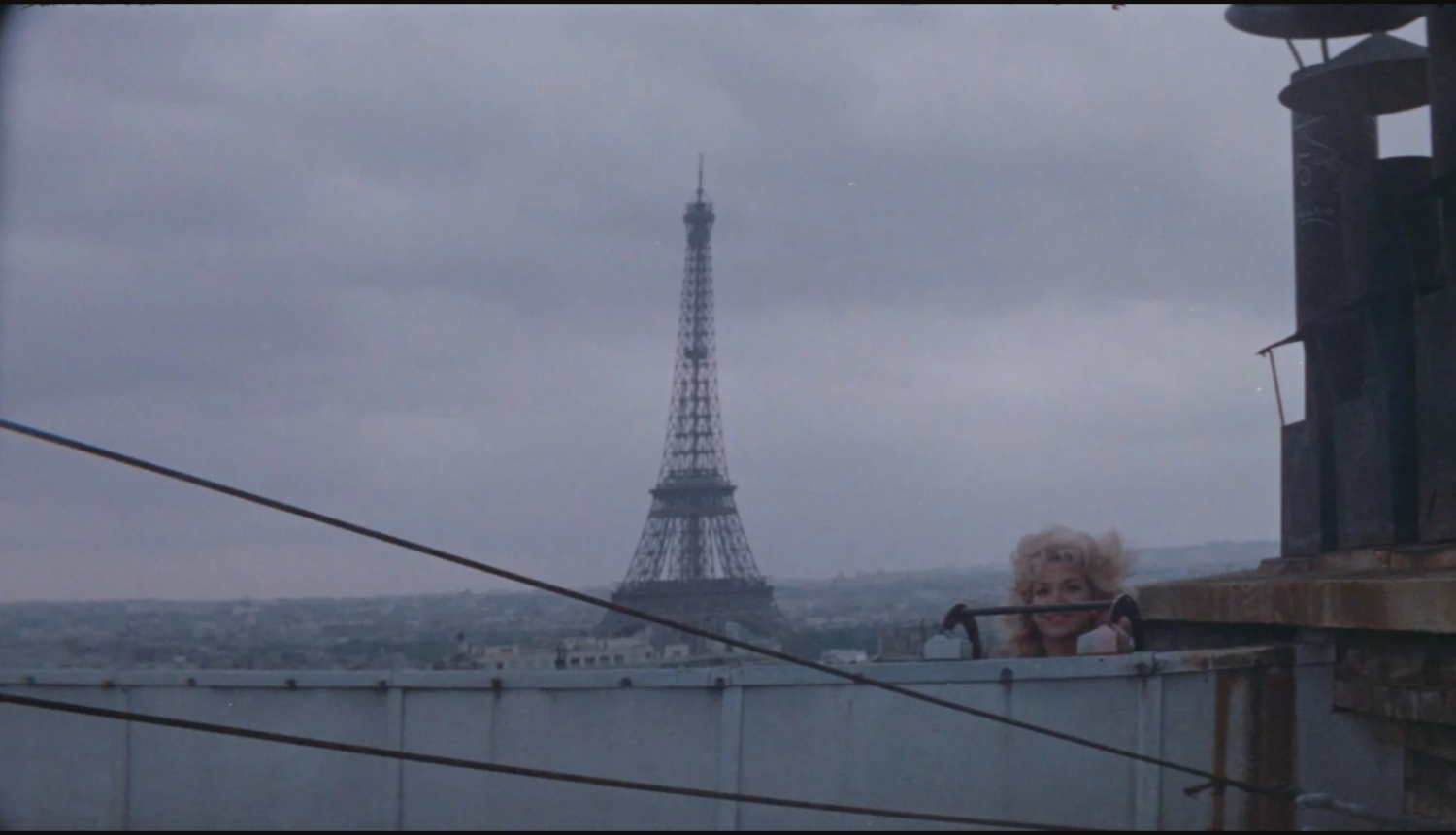 “Parīzes manekeni” kadra daļa. Skats uz Parīzi, Eifeļa torni un sievieti no jumta.