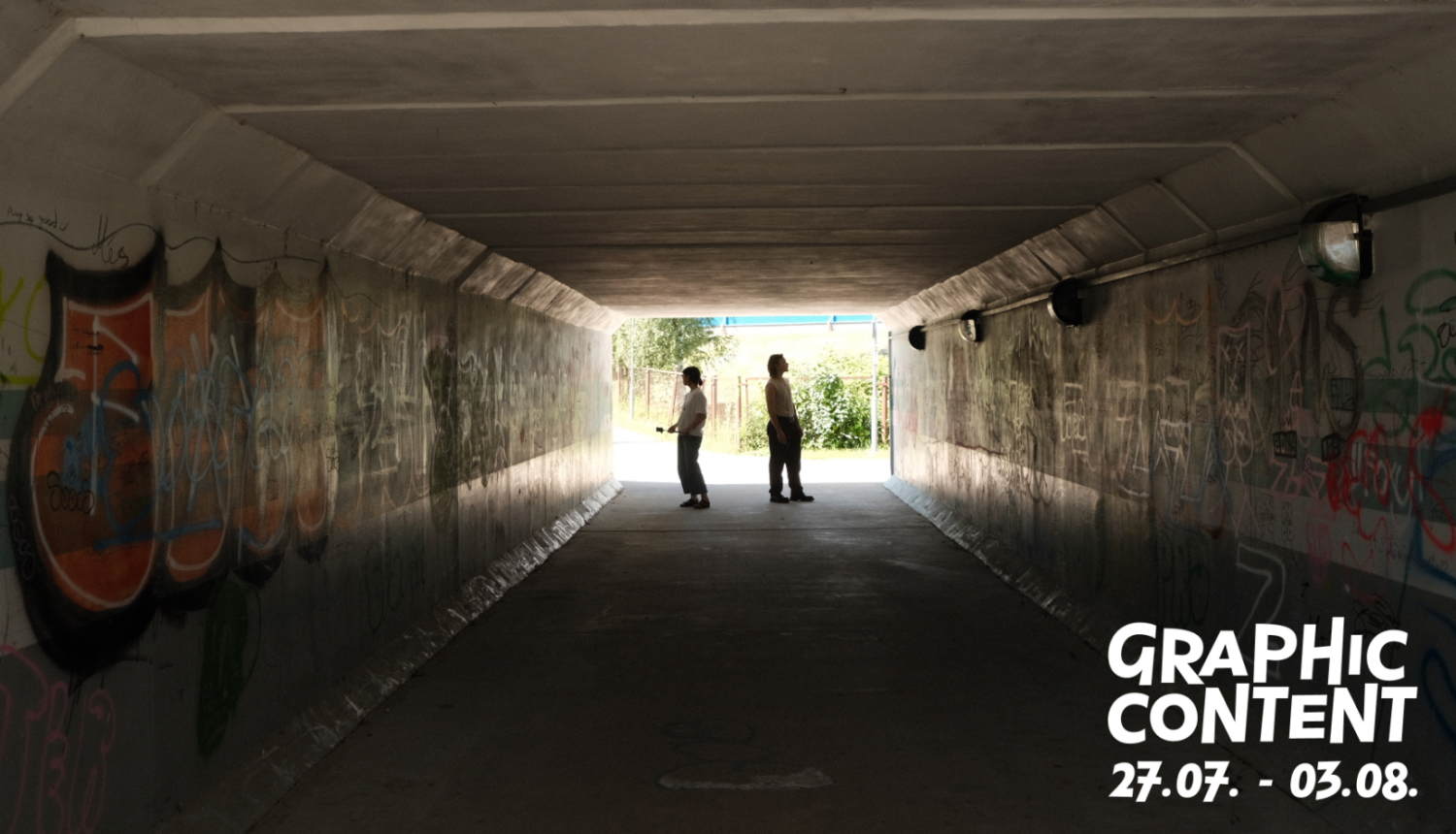 Izstādes “Graphic Content” publicitātes foto ar diviem cilvēkiem, kas apbrīno grafiti tunelī. Foto: Mike Saijo
