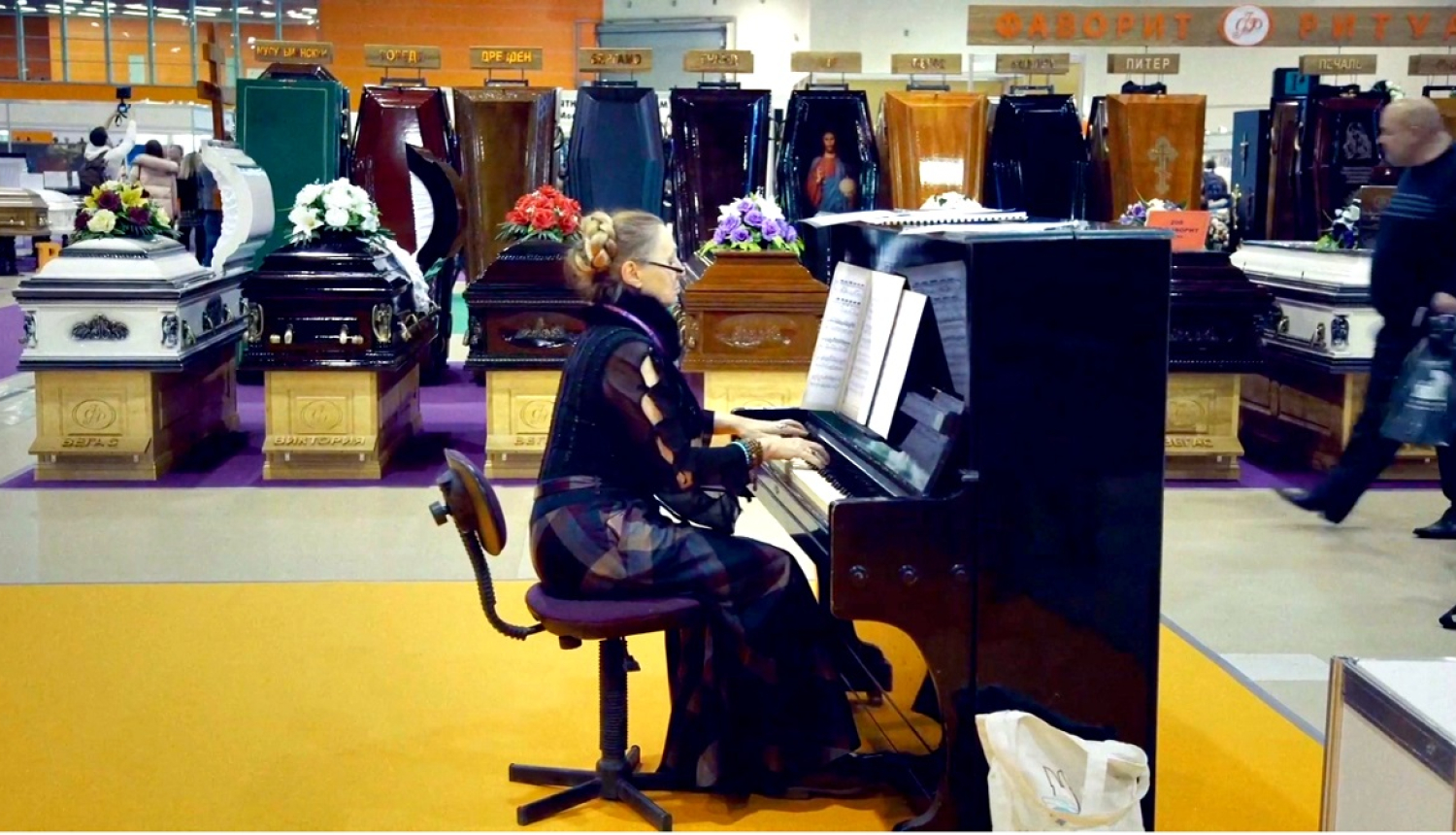 Kadrs no Dāvja Sīmaņa dokumentālās filmas „Frankenšteins 2.0” - sieviete sēž pie klavierēm apbedīšanas biroja telpās