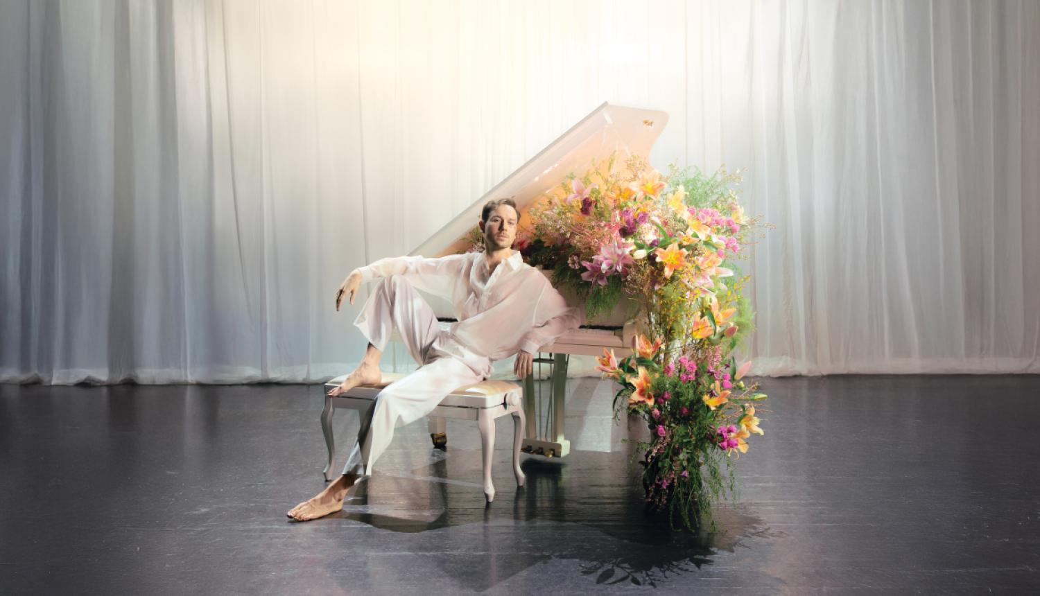 Iestudējuma afiša. Aktieris Maksims Busels pie baltam klavierēm