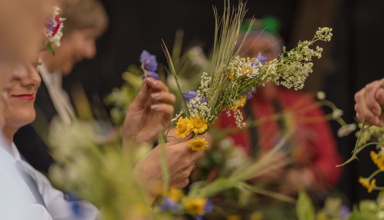 Cilvēki pin Jāņu vainagus