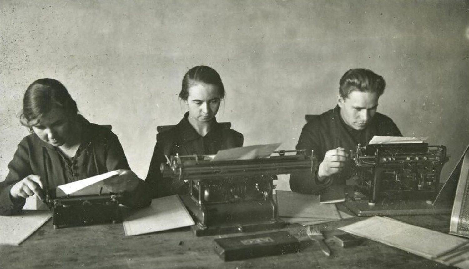 Trīs arhīva darbinieki pie rakstāmmašīnām