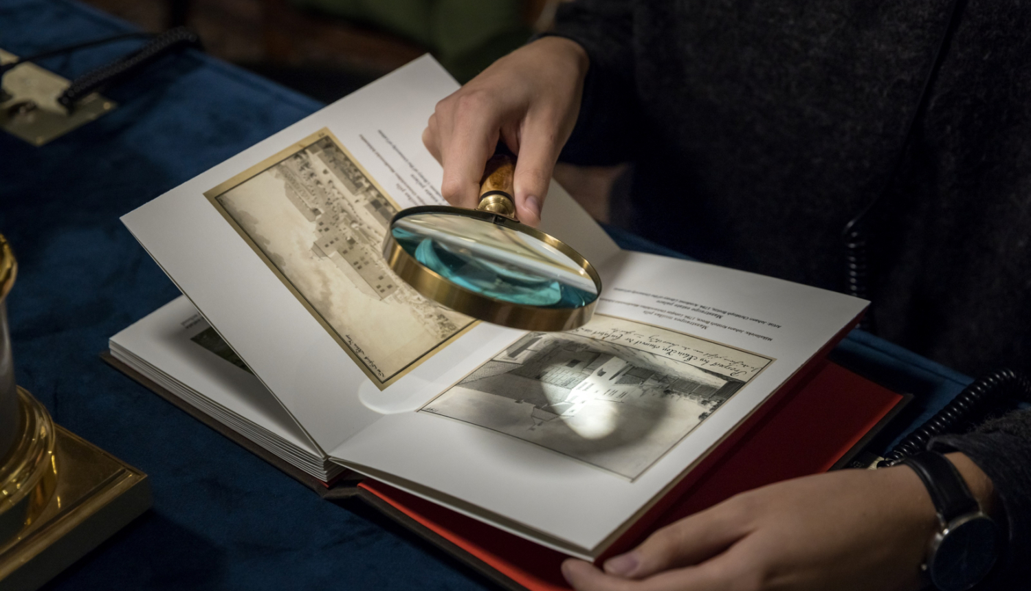 Persona ar palielināmo stiklu pēta saturu grāmatā