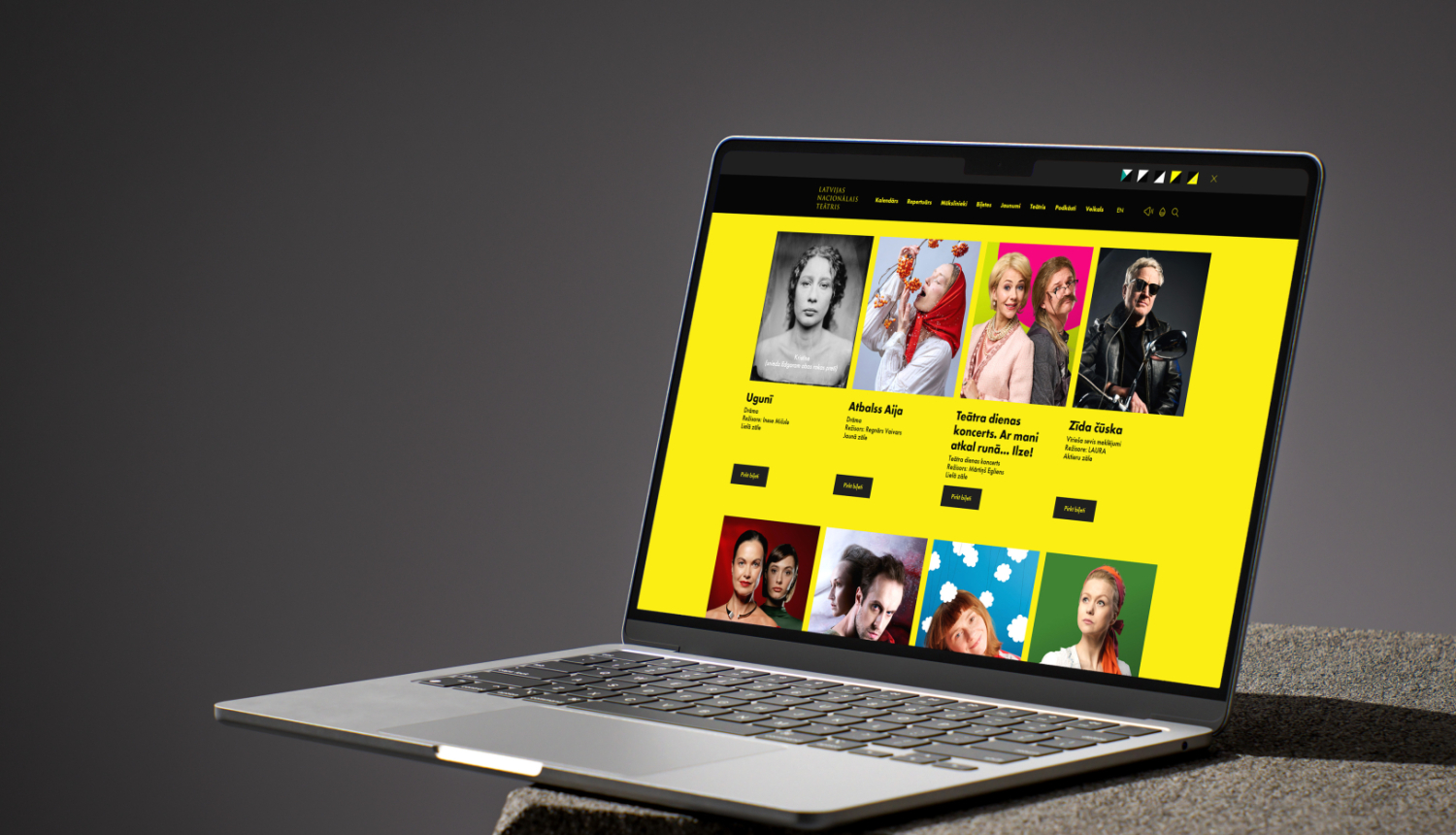 Dators uz galda. Ekrānā redzams Latvijas Nacionālā teātra repertuāra saraksta skats ar izrāžu reklāmas fotogrāfiju galeriju