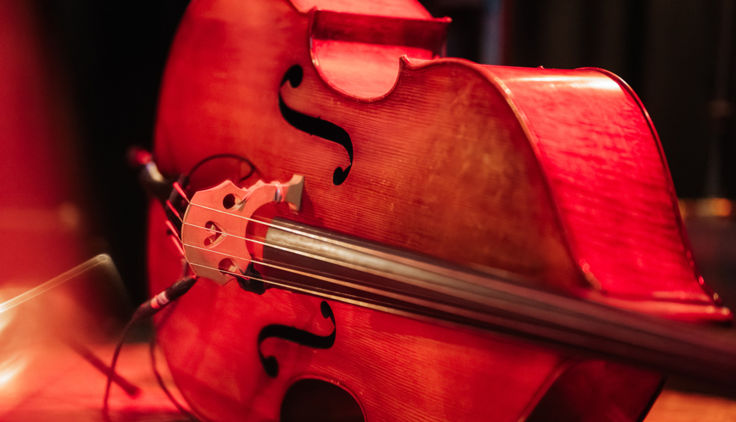 Uz skatuves guļošs kontrabass oranžās lampu gaismās