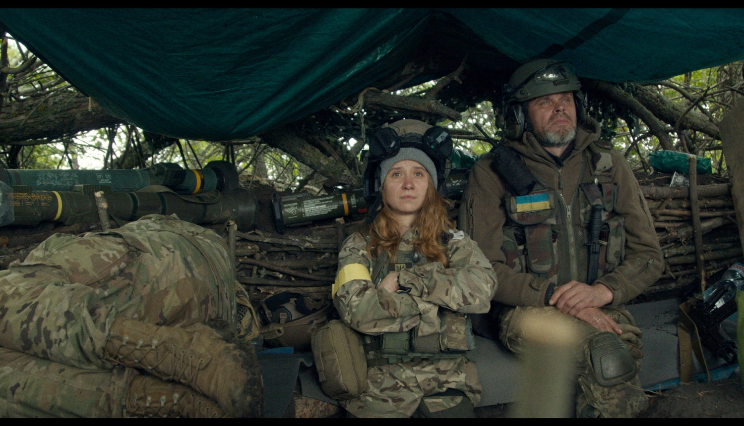 Kadrs no ukraiņu dokumentālistes Alisas Kovalenko jaunākās filma “Manu mīļo Teo” (My Dear Theo), kadrā telsts ar armijas ekipējumu un diviem armijas formastērpā tērptiem cilvēkiem