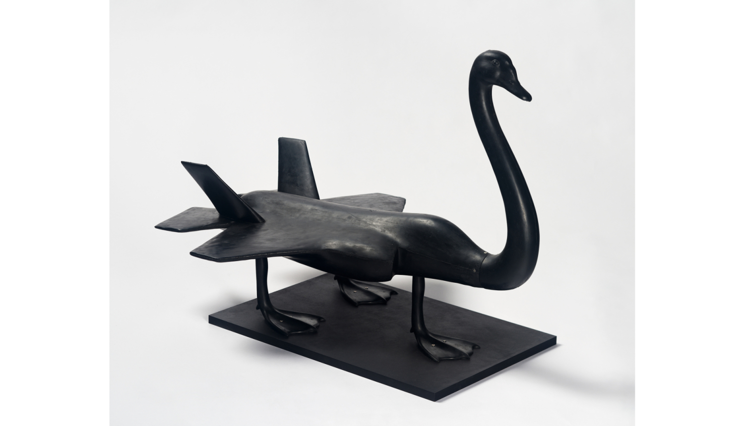 Darbs no izstādes - Melns gulbis ar ķermeni lidmašīnas formā un trīs kājām, kas atgādina lidmašīnas riteņus
