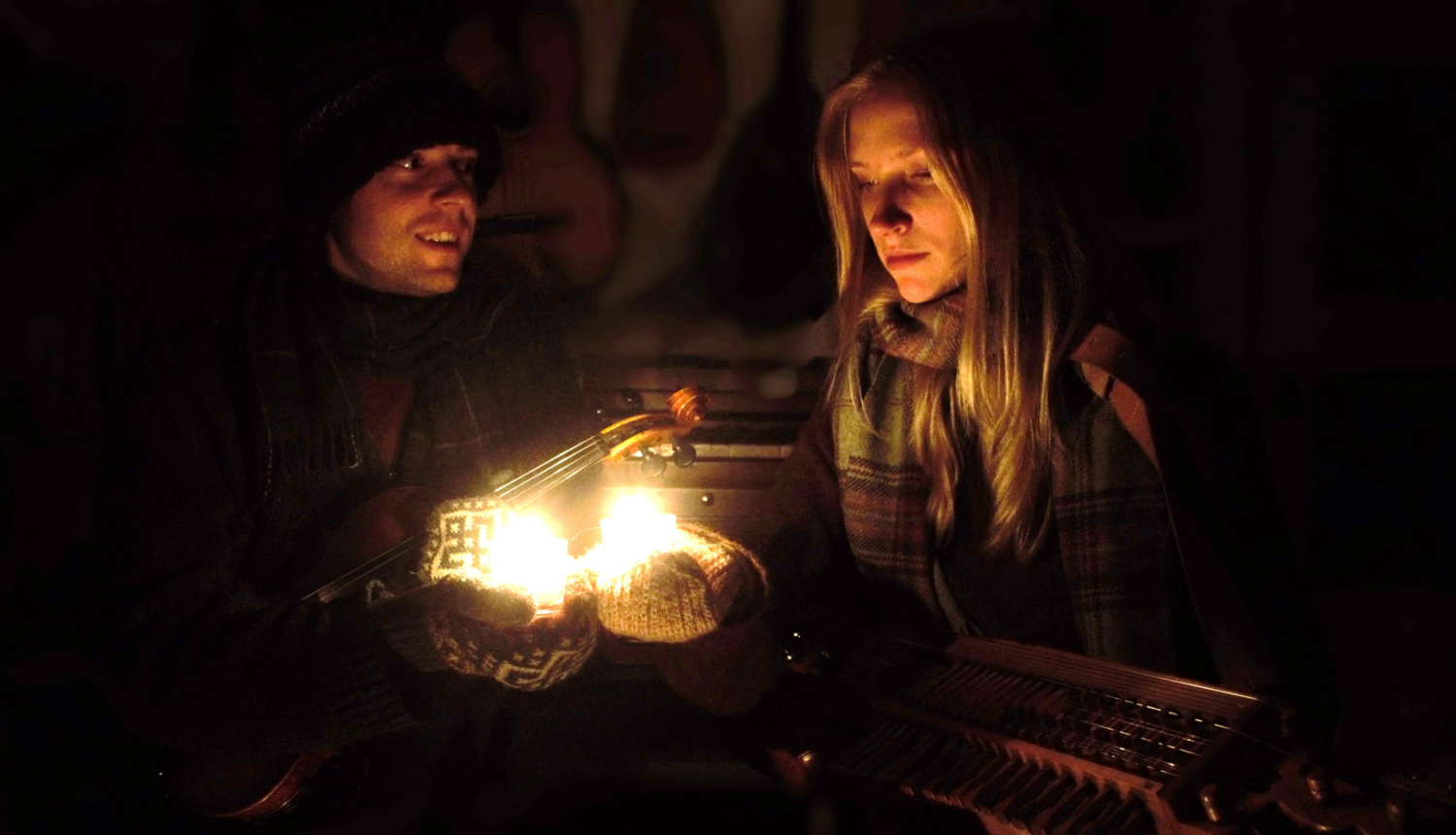 Cilvēki ziemas naktī pie aizdegtas laternas