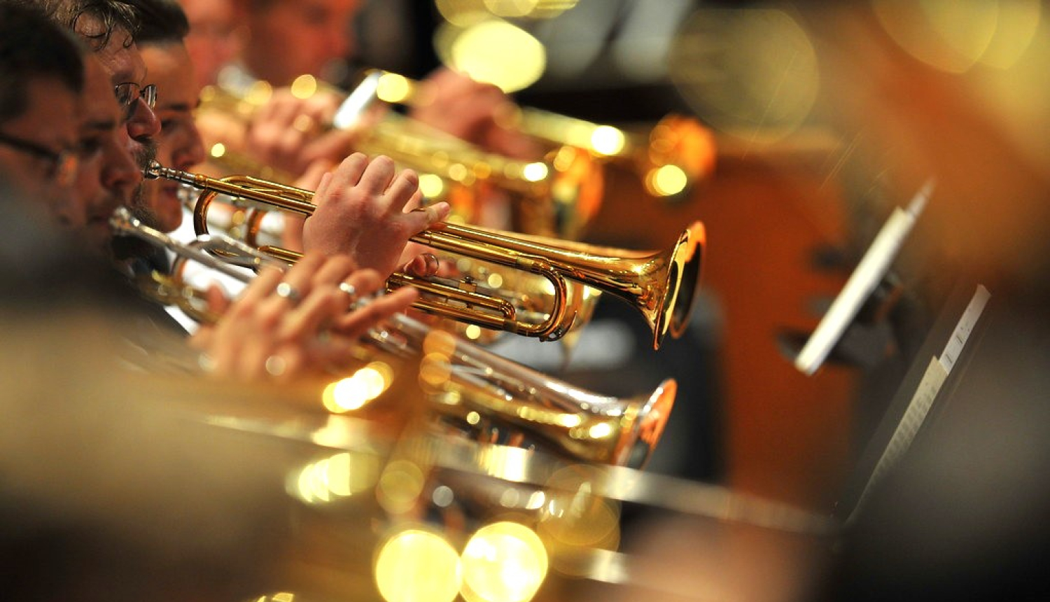 Orķestra dalībnieki pūšaminstrumentu grupā spēlē koncertā