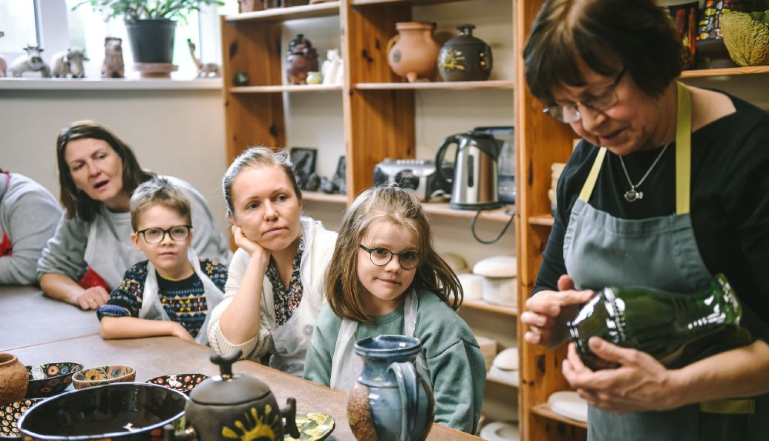 Keramikas rokdarbu meistardarbnīca/nodarbība - kadrā apmeklētāji un keramiķe
