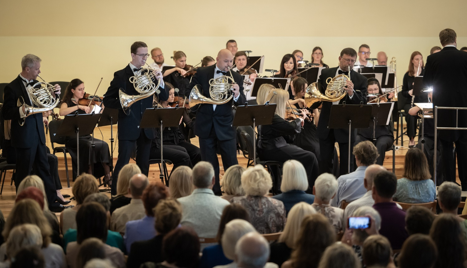 Skatītāji klausās kā uz skatuves Liepājas Simfoniskais orķestris koncertē