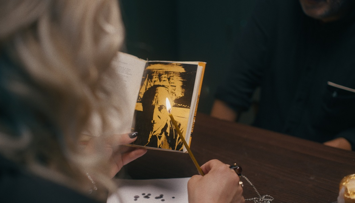 Kadrs no režisora Jāņa Ābeles dokumentālās filma “Testaments”, kadrā cilvēks, kas tur rokā grāmatiņu un sveci