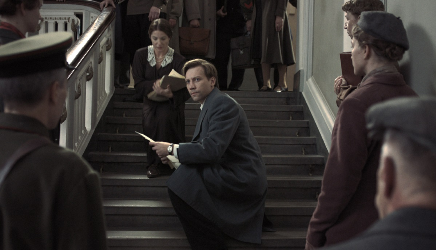 Kadrs no filmas “Divi prokurori” (Two Prosecutors), kadrā galvenās lomas atveidotājs un citi cilvēki uz ēkas kāpnēm