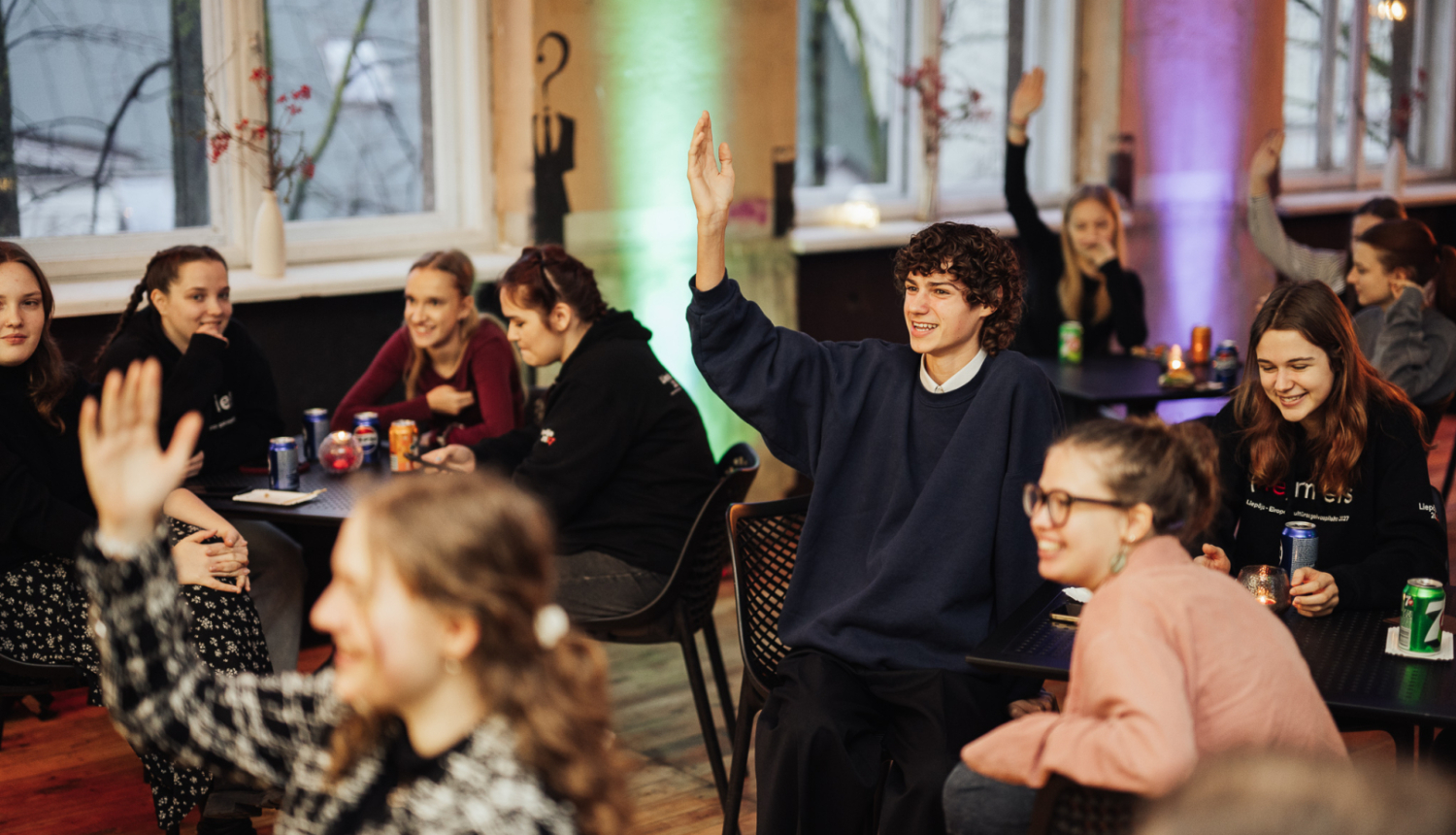 Tartu jaunieši sēžot, dzerot limonādes, daļa pacēluši roku