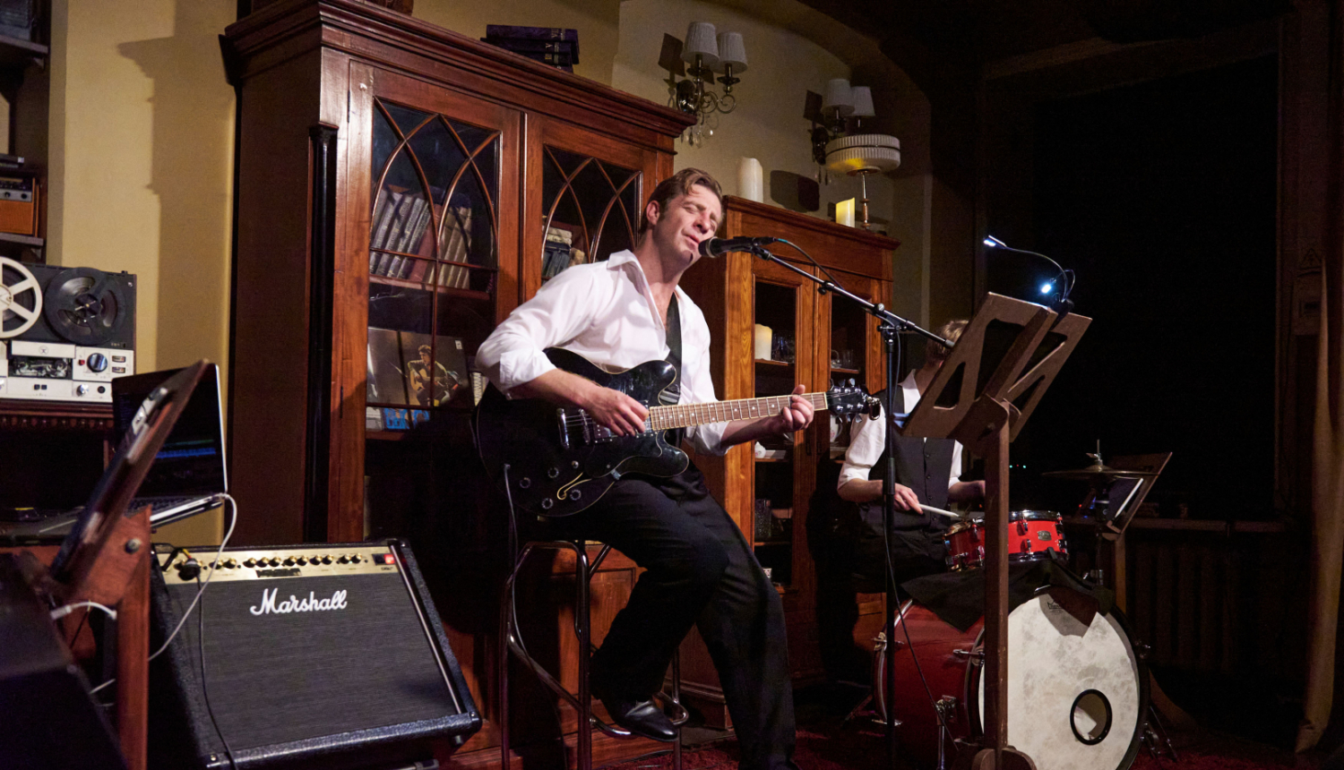 Aktieris uz skatuves spēlē ģitāru un dzied