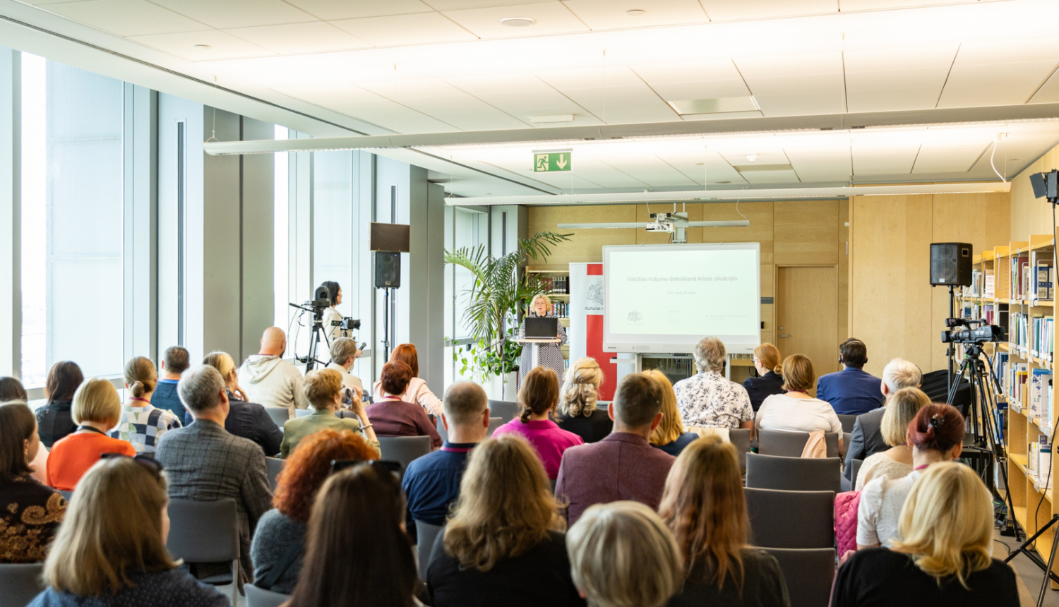 Mācību apmeklētāji klausās priekšlasījumu bibliotēkas telpā