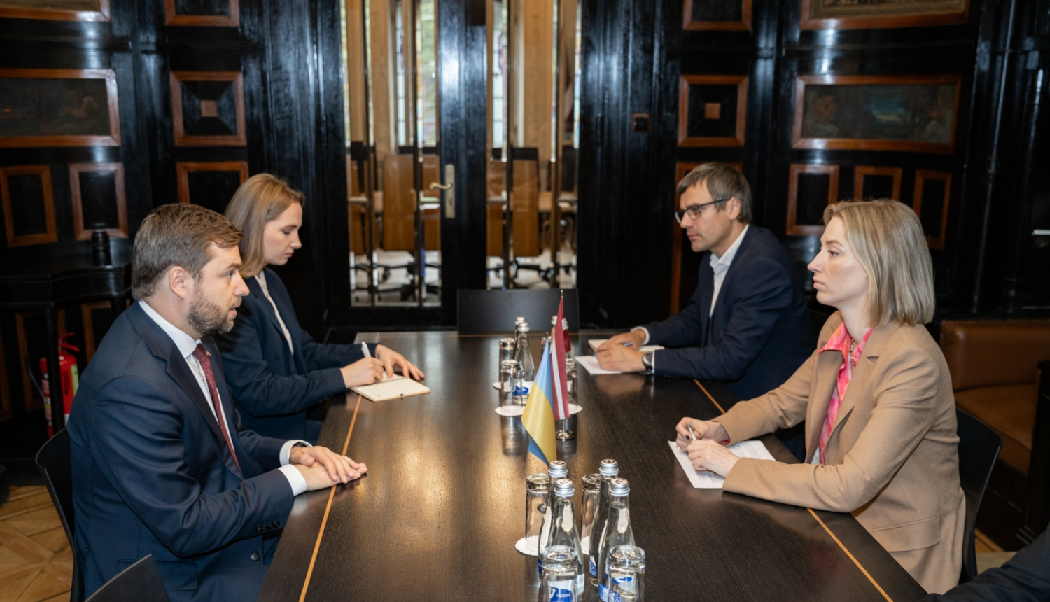 Četri cilvēki sanāksmju telpā pie galda