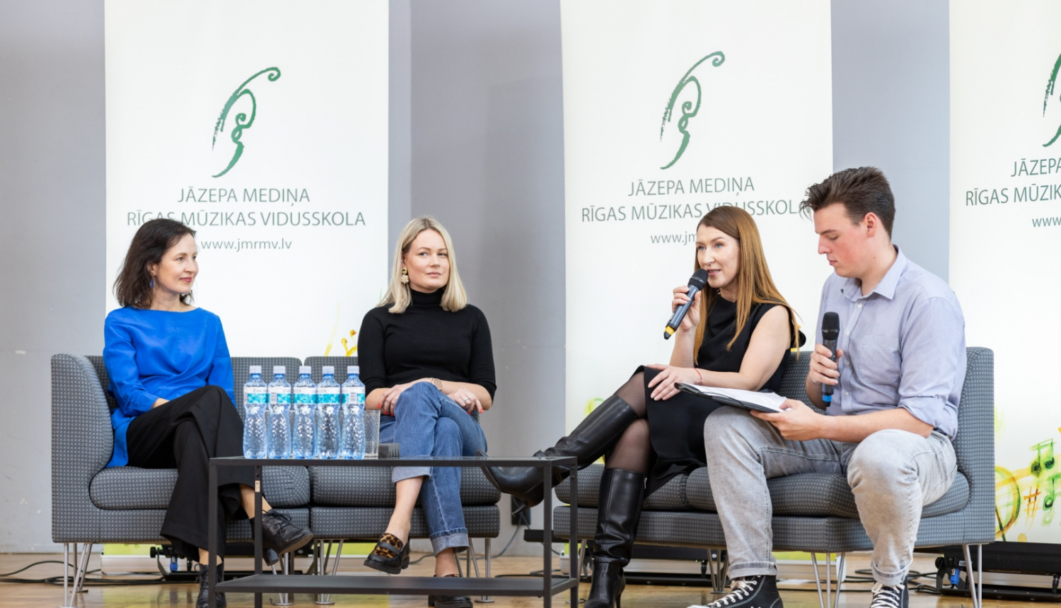 Četri cilvēki diskutē uz skatuves