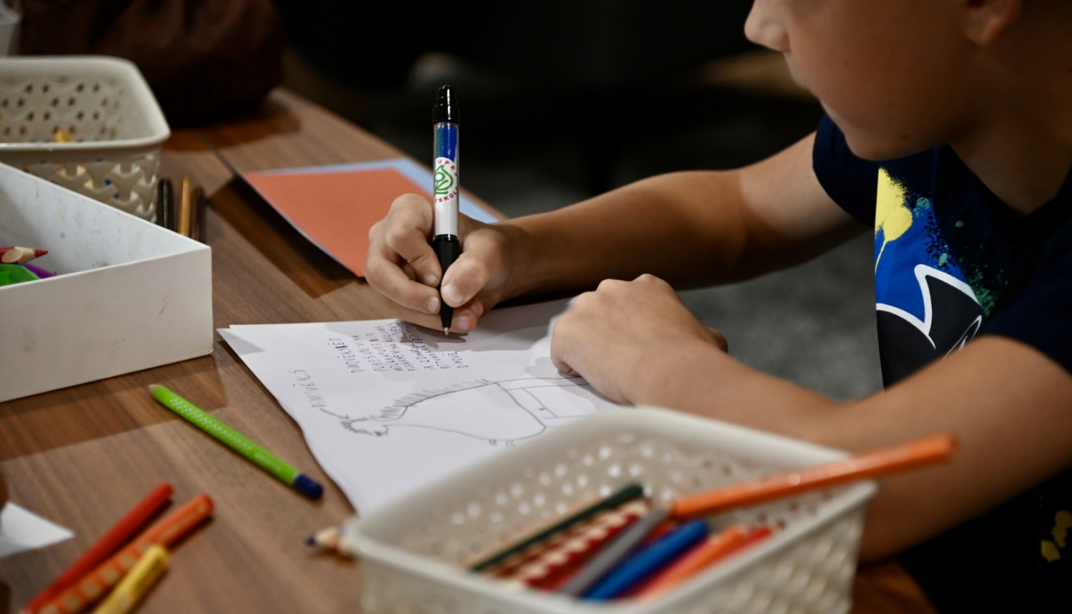 Bērns pie galda ar rakstāmpiederumiem