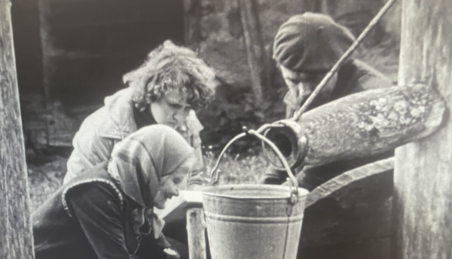 Kadrs no filmas, trīs cilvēki pumpē ūdeni