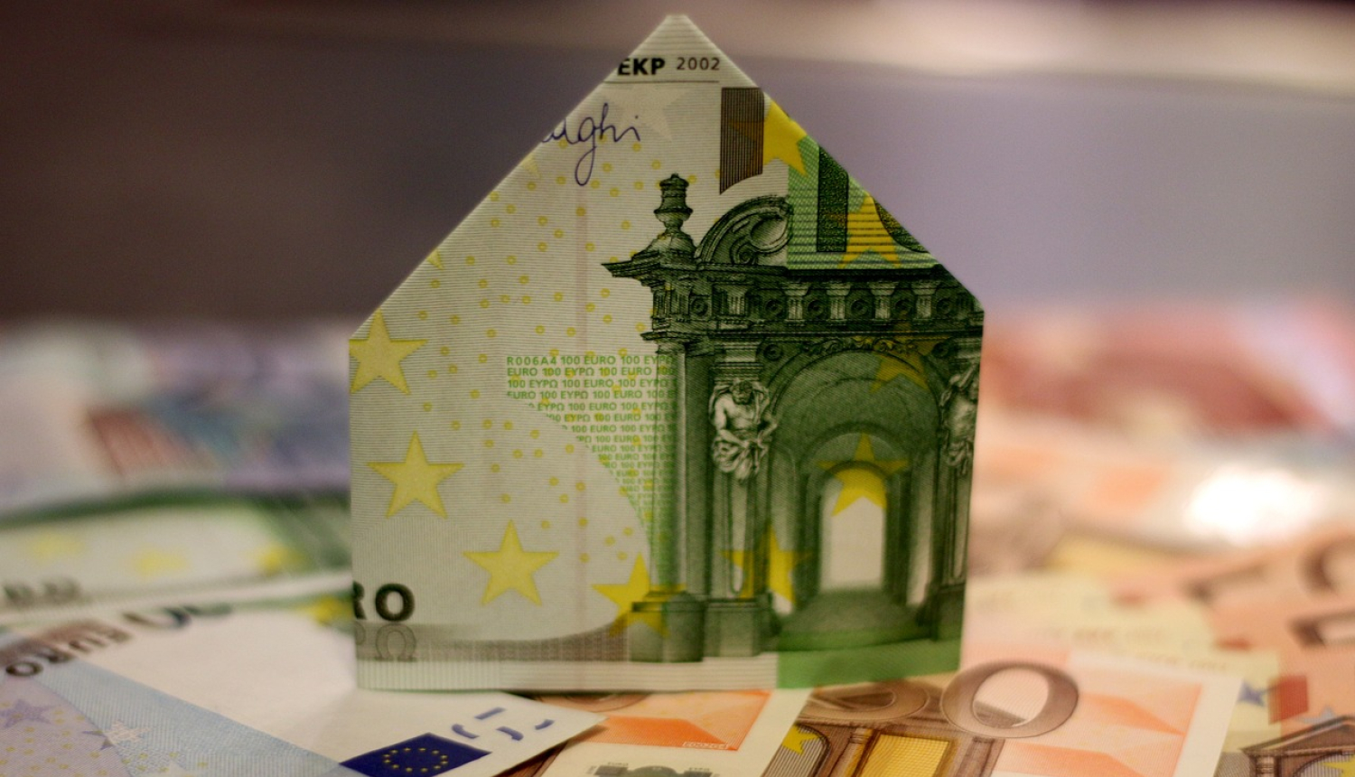 Mājiņas siluets uzlocīts no naudaszīmēm