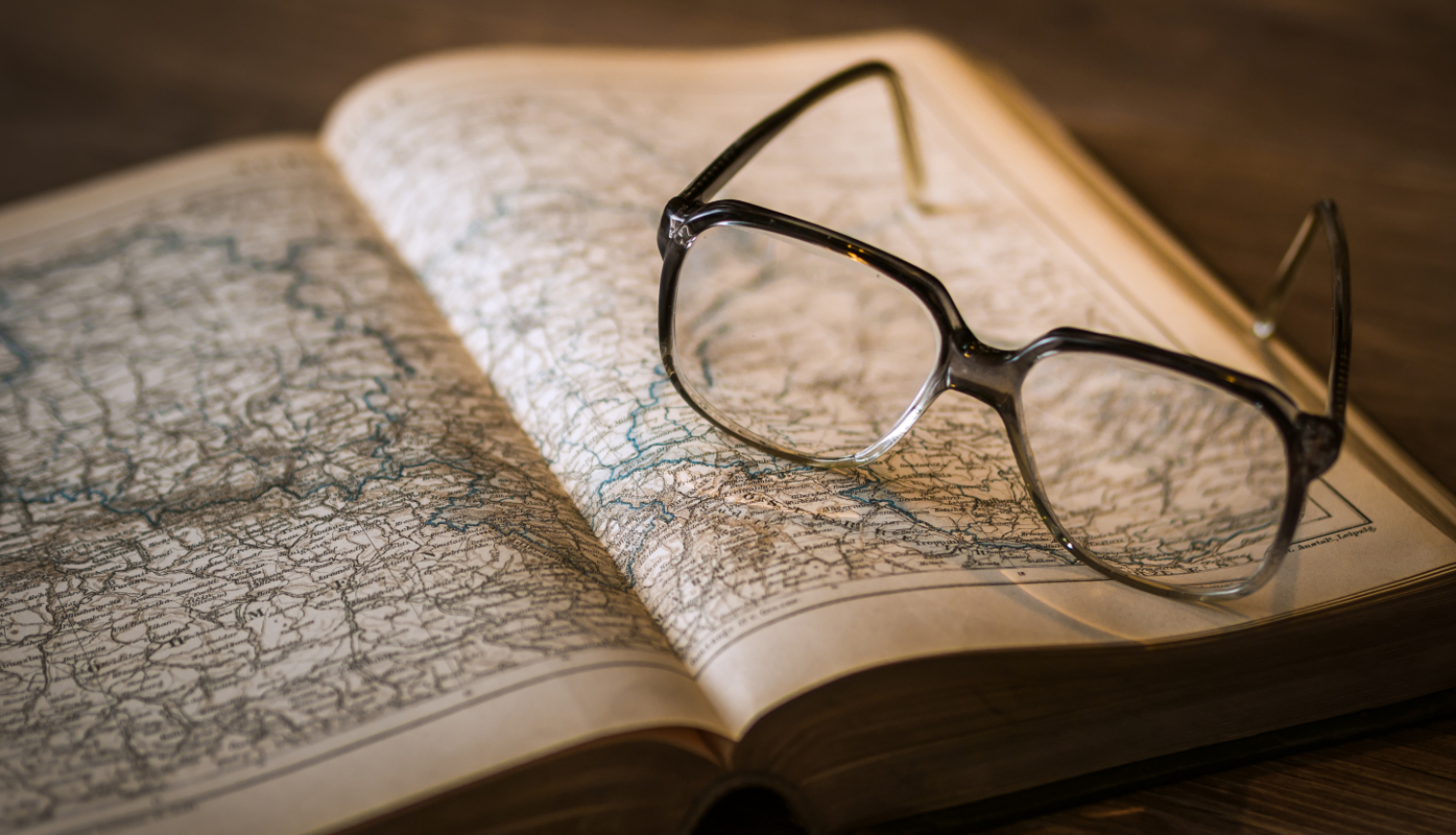 Smalka karte atvērta grāmatā, uz tās novietotas brilles.