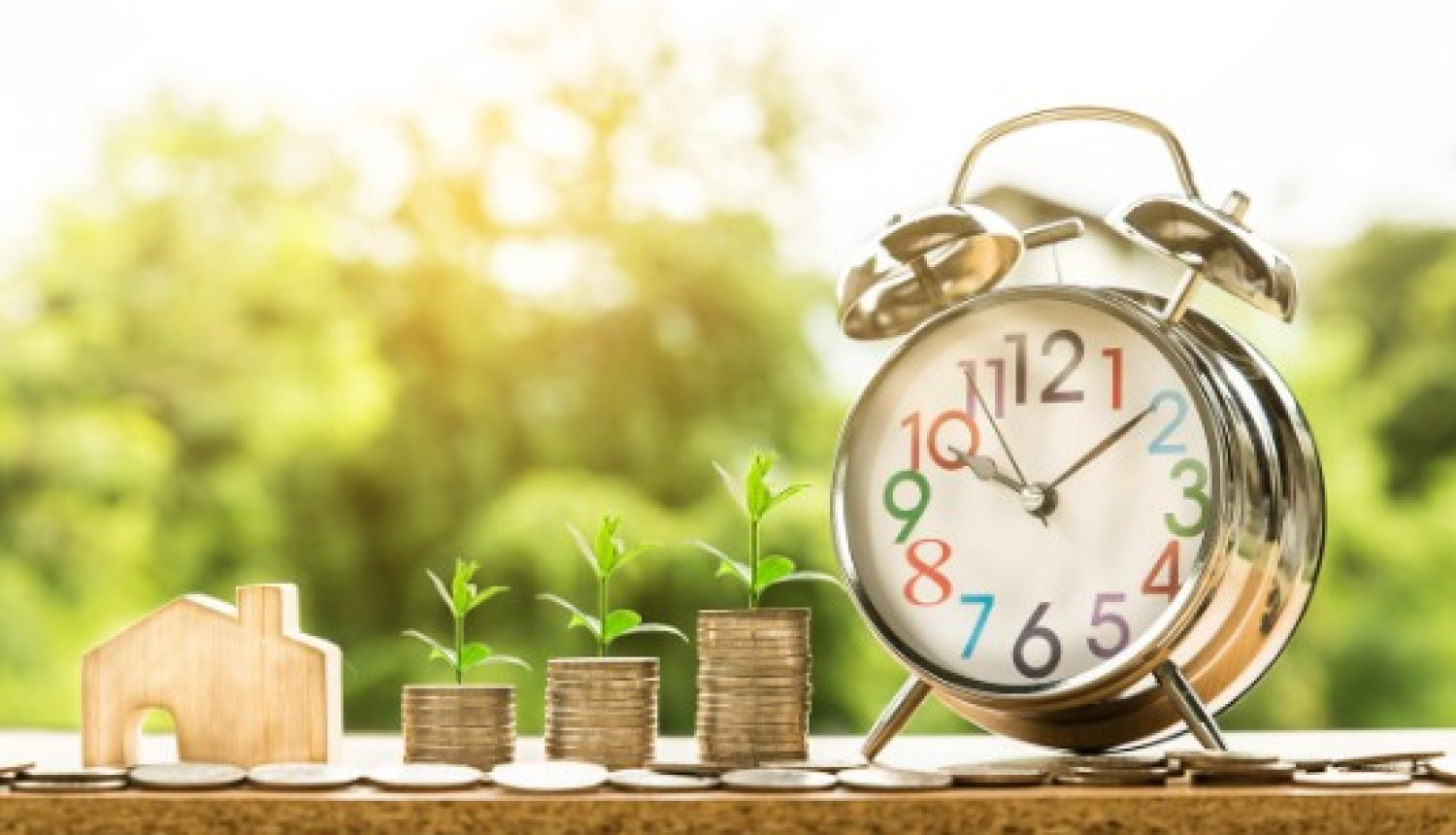 Attēls ar pulksteni un naudas čupām, kurām blakus ir mazs mājas modelis