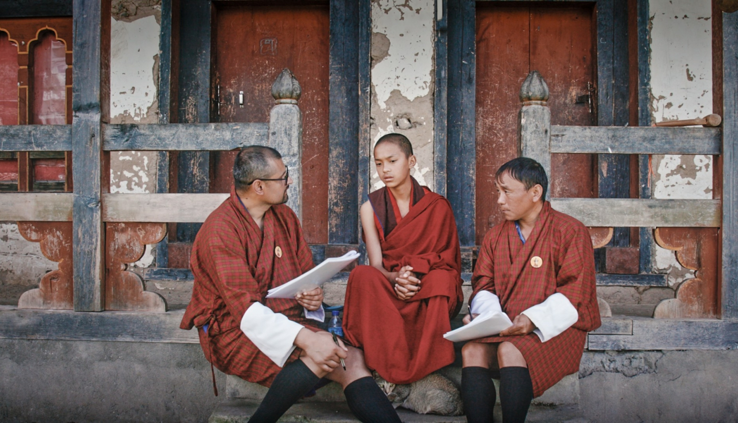 Kadrs no filmas, trīs cilvēki sēž uz ielas